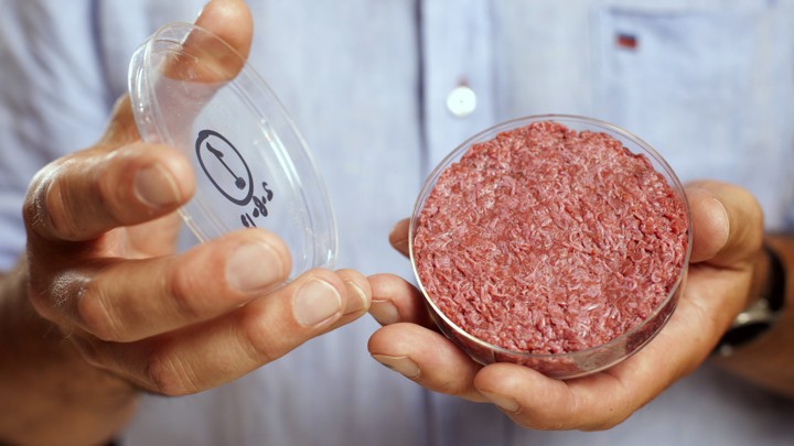 Professor Mark Post holds the world's first lab-grown beef burger during a launch event in west London